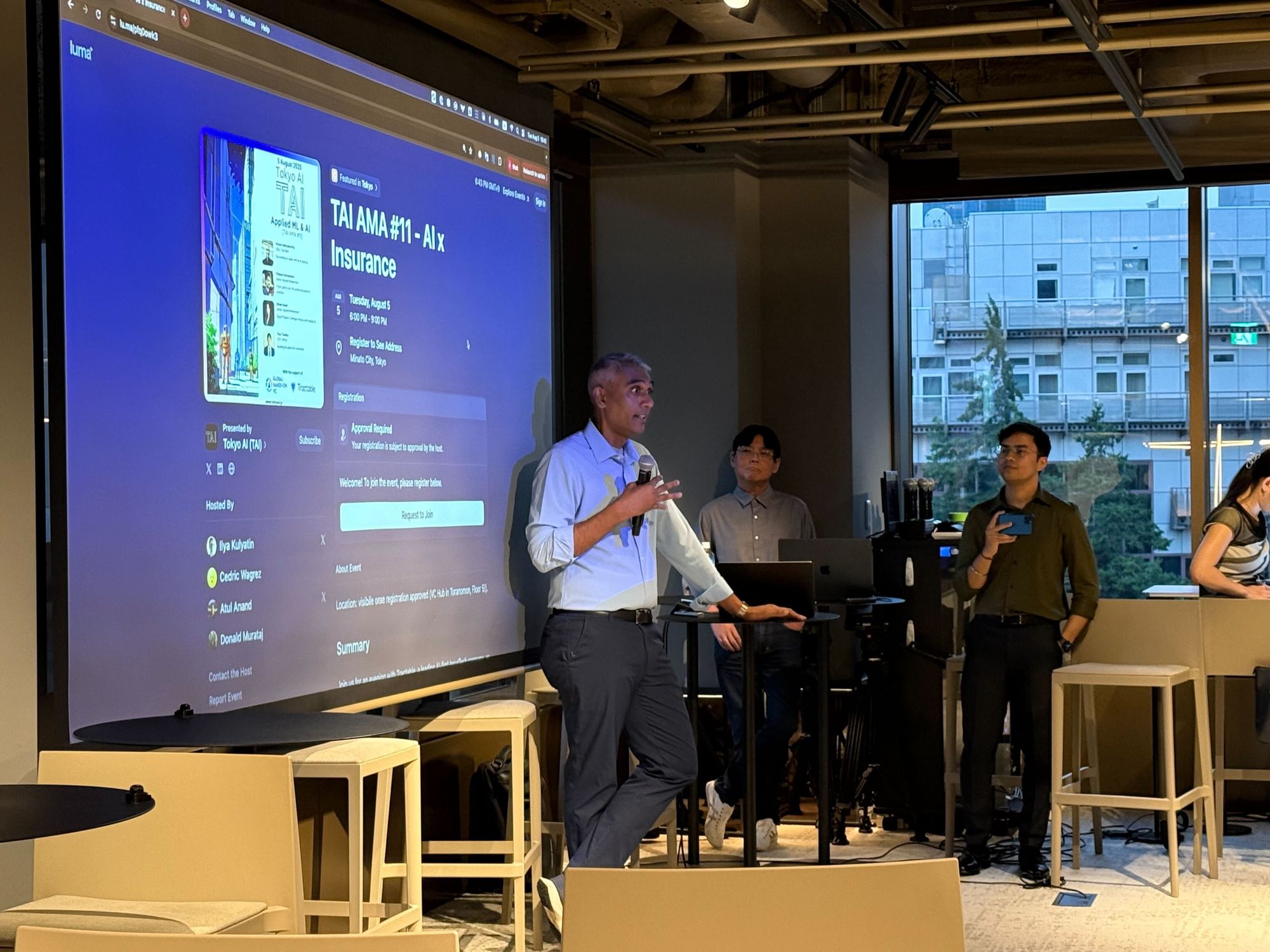 「AI x Insurance」のイベントページを投影したスクリーンの横で話す登壇者